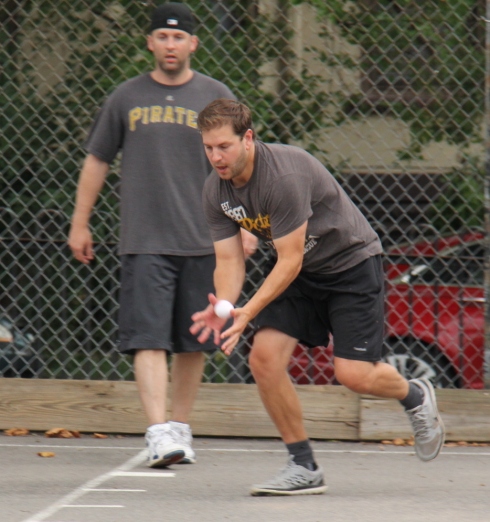 Tom scoops up a ball in center field with Mike looking on 